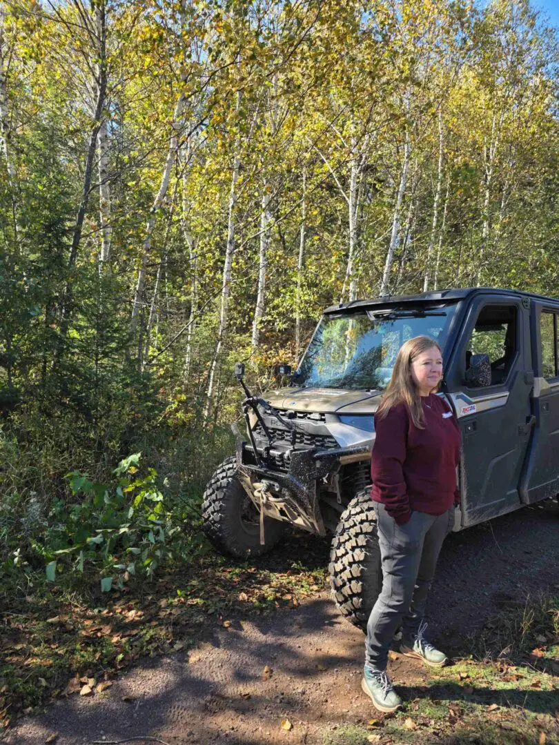 Woman standing by off-road vehicle in forest