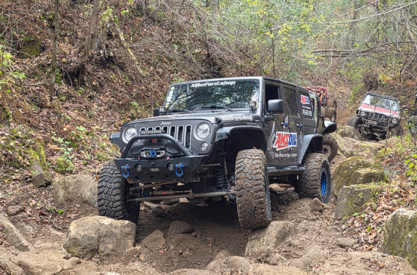 A black Jeep Wrangler navigating rocky off-road terrain.
